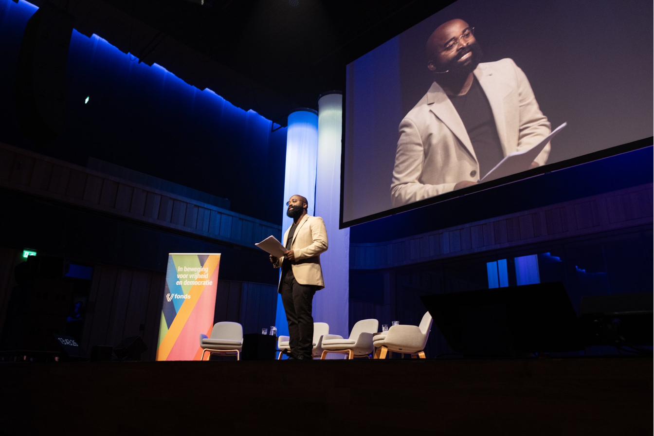 Kiza Magendane leidt een gesprek op het podium